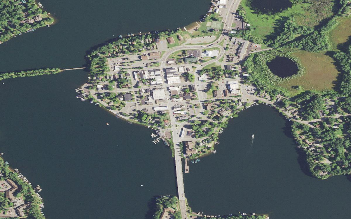 Aerial view of downtown Minocqua on its near-island, with the Highway 51 causeway crossing the lake to the south and the old rail grade running west