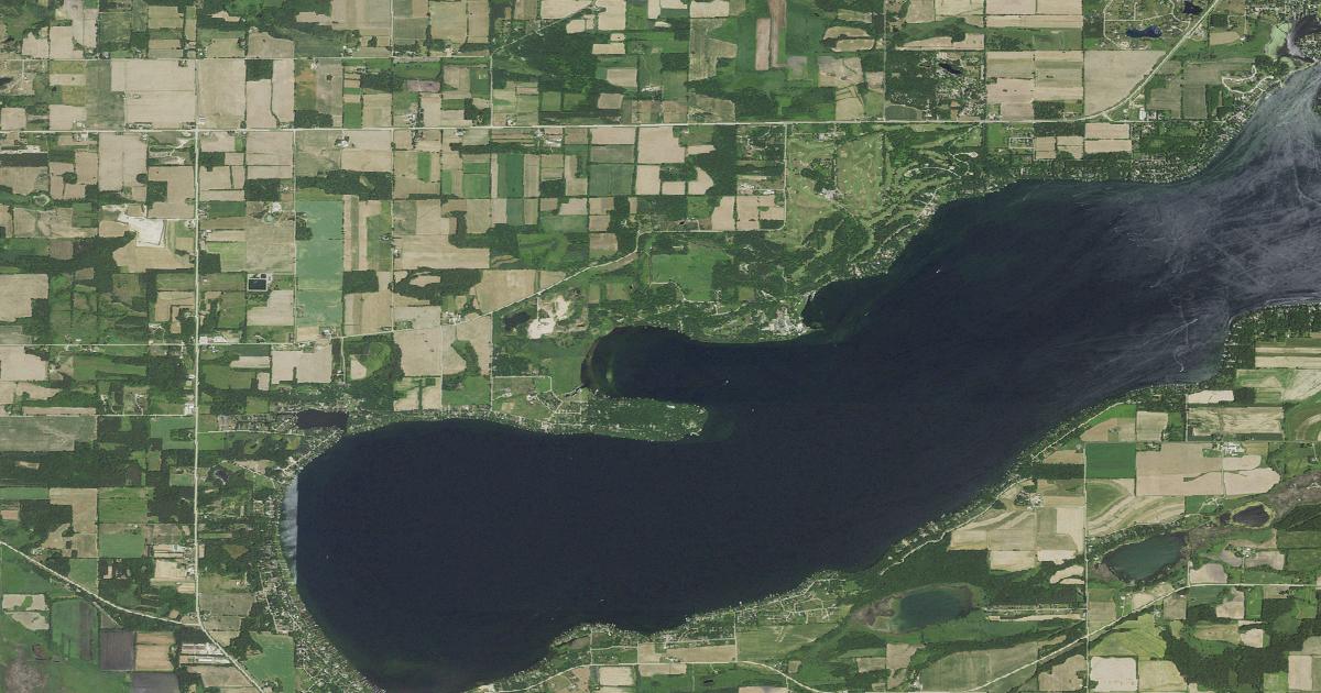 Aerial view of Big Green Lake running east to west, the village of Green Lake at its east end and farmland around the rest