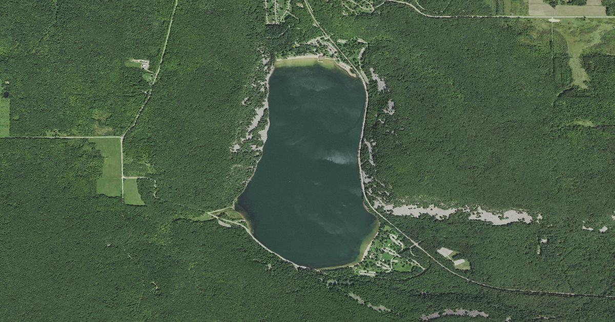 Aerial view of Devil's Lake filling a gorge between two forested bluffs, pale quartzite talus fields visible along both sides