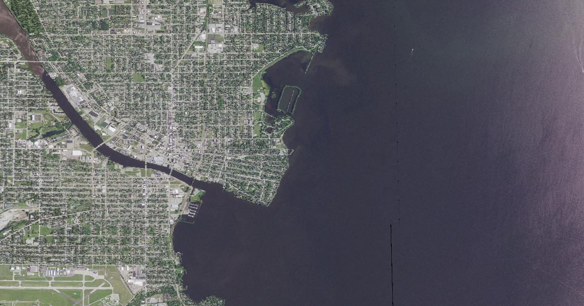 Aerial view of Oshkosh and the mouth of the Fox River on the west shore of Lake Winnebago, open water filling the eastern half of the frame